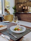 Gedeckter Tisch mit angerichtetem Gericht und Weißwein im Naturresort Puradies, Leogang, Salzburger Land Gericht mit Tomate und Rucola, Weißwein am Tisch, Puradies Leogang