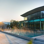 Person am Außenpool des Heaven Spa bei Sonnenaufgang, Puradies Leogang