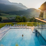 Person im Infinity Pool des Heaven Spa bei Sonnenaufgang, Puradies Leogang