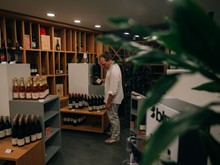 Person beim Weinbetrachten in der Greisslerei (Hotelshop) – Naturresort Puradies, Leogang, Salzburger Land Person beim Weinbetrachten in der Greisslerei (Hotelshop), Puradies Leogang