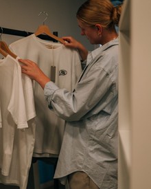 Person beim Betrachten von T-Shirts in der Greisslerei (Hotelshop) – Naturresort Puradies, Leogang, Salzburger Land Person beim Betrachten von T-Shirts in der Greisslerei, Puradies Leogang
