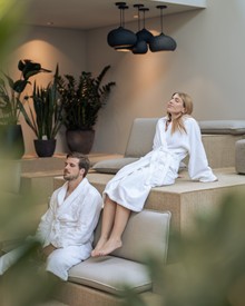 Entspannende Personen in Bademänteln in der Kaminlounge, Heaven Spa