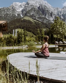 Person in Meditationshaltung am Naturbadeteich, Naturresort Puradies in Leogang