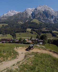 Mountainbiker in Steilkurve vor Bergpanorama, Naturresort Puradies in Leogang