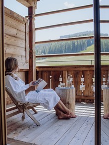 Person im Bademantel entspannt auf dem Balkon des Heaven Spa im Naturresort Puradies