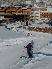 Skifahrerin vor Naturresort Puradies im Winter, Leogang