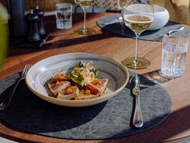 Gedeckter Tisch mit angerichtetem Gericht und Weißwein im Naturresort Puradies, Leogang, Salzburger Land Angerichtetes Gericht mit Weißwein am gedeckten Tisch, Puradies Leogang