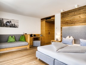 Sitzbank und Doppelbett mit Kleiderschrank in der Deluxe Suite im Naturresort Puradies