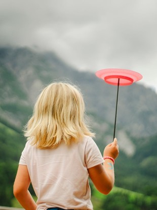 Child Balancing a Spinning Plate Against the Mountain Panorama at Naturresort Puradies, Leogang, Salzburger Land Child balancing a spinning plate against mountains, Puradies Leogang