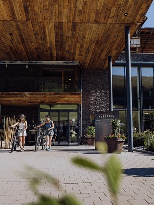Two Mountain Bikers at the Main Entrance – Naturresort Puradies, Leogang, Salzburger Land Two mountain bikers at the main entrance, Naturresort Puradies in Leogang