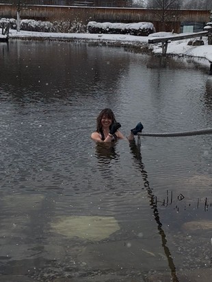 Edith Aigner beim Eisbaden im Naturbadeteich Heaven Spa, im Hintergrund das Traumquartier – Naturresort Puradies, Leogang, Salzburger Land Edith Aigner beim Eisbaden im Naturbadeteich Heaven Spa, Puradies Leogang