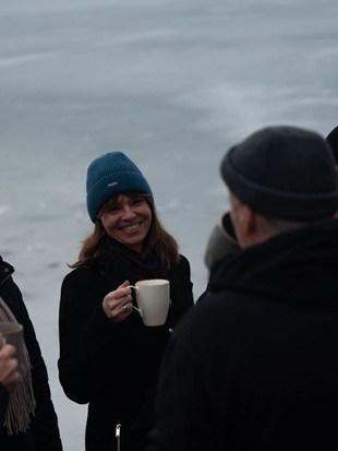 Edith Aigner mit Gruppe bei warmen Getränken vor zugefrorenem Wasser – Retreat, Naturresort Puradies, Leogang, Salzburger Land Edith Aigner mit Gruppe bei warmen Getränken, Retreat Puradies Leogang