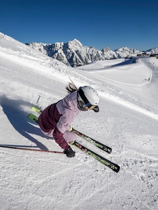 Skifahrerin in Kurve mit Bergpanorama, Naturresort Puradies in Leogang