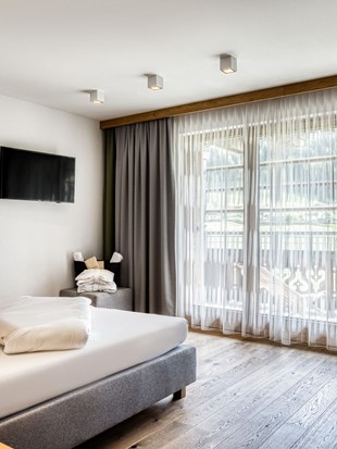 Doppelbett mit Fernseher und Terrassenzugang in der Deluxe Suite im Naturresort Puradies