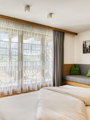 Doppelbett mit Sitzbank und Terrassenzugang in der Deluxe Suite im Naturresort Puradies