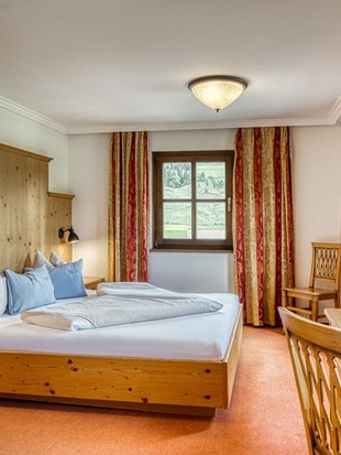 Blick auf Doppelbett und Schreibtisch im Genießer Familienzimmer im Naturresort Puradies