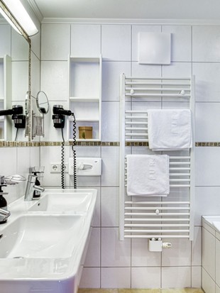 Badezimmer mit Doppelwaschbecken und Badewanne im Genießer Familienzimmer im Naturresort Puradies