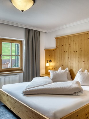 Doppelbett mit Holzverkleidung im Genießerzimmer im Naturresort Puradies