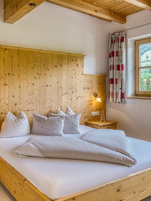 Doppelbett mit Holzkopfteil und Bergblick im Genießerzimmer im Naturresort Puradies