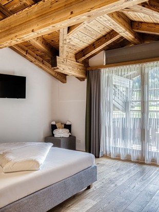 Doppelbett mit Holzbalkendecke und Balkonzugang im Natur Loft im Naturresort Puradies