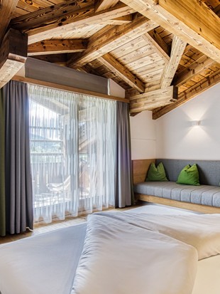 Doppelbett mit Sitzbank und Balkonzugang im Natur Loft im Naturresort Puradies
