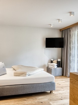 Doppelbett mit Fernseher und Balkonzugang in der Premium Suite im Naturresort Puradies