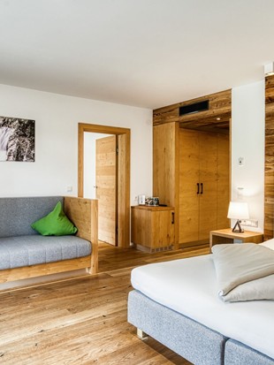 Sitzbank und Doppelbett mit begehbarem Kleiderschrank in der Premium Suite im Naturresort Puradies