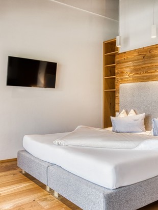 Doppelbett mit Fernseher und Blick in den Wohnbereich in der Privat Spa Suite Wolke 7 im Naturresort Puradies Doppelbett mit Fernseher und Blick in den Wohnbereich in der Privat Spa Suite Wolke 7 im Naturresort Puradies