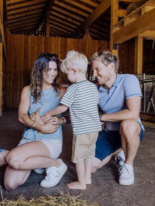 Familie beim Streicheln eines Kaninchens am Bio-Bauernhof Embachhof, Naturresort Puradies, Leogang, Salzburger Land Familie mit Kaninchen im Stall des Bio-Bauernhofs Embachhof, Puradies Leogang