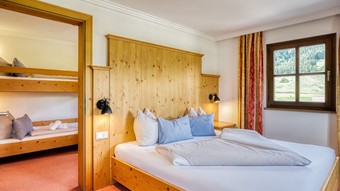 Doppelbett mit Blick ins Kinderzimmer mit Etagenbett im Genießer Familienzimmer im Naturresort Puradies Doppelbett mit Blick ins Kinderzimmer im Genießer Familienzimmer im Naturresort Puradies