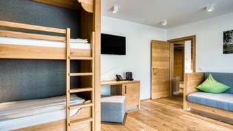 Zusätzlicher Wohnbereich mit Etagenbett und Sofa in der Premium Suite im Naturresort Puradies Zusätzlicher Wohnbereich mit Etagenbett und Sofa in der Premium Suite im Naturresort Puradies