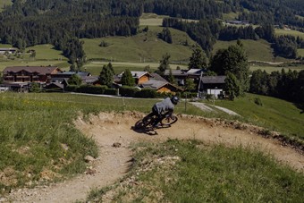 Mountainbiker in Steilkurve vor Bergpanorama, Naturresort Puradies in Leogang
