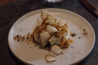 Fein angerichtetes Gericht mit Röstzwiebeln und Weißweinglas, Naturresort Puradies, Leogang, Salzburger Land Angerichtetes Gericht mit Röstzwiebeln und Weißwein, Puradies Leogang