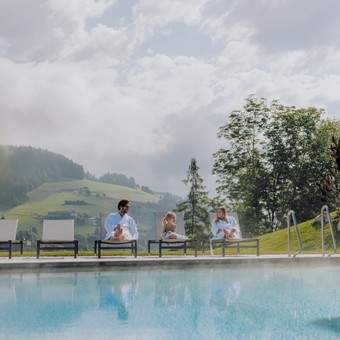 Familie im Bademantel am Infinity Pool im Sommer, Puradies Leogang