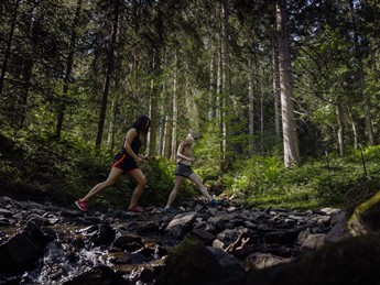 Zwei Wanderinnen überqueren Waldbach, Naturresort Puradies in Leogang
