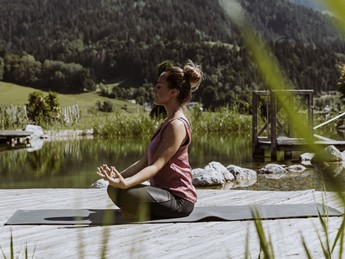Person in Meditationshaltung am Naturbadeteich, Naturresort Puradies in Leogang
