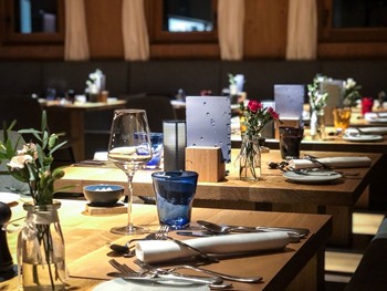 Hotelrestaurant mit gedeckten Tischen bei Abendstimmung, Puradies Leogang