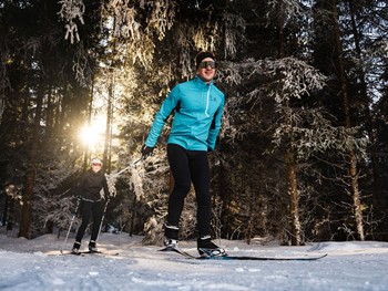 Zwei Langläufer auf Loipe im Winterwald, Naturresort Puradies in Leogang
