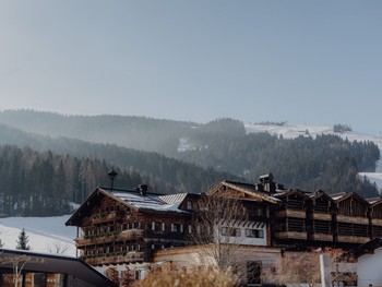 Hotelgebäude im Winter, im Hintergrund Skipiste, Puradies Leogang