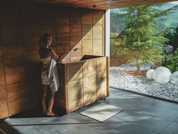 Person Preparing the Infusion at the Sauna Stove at Heaven Spa – Naturresort Puradies, Leogang, Salzburger Land Person preparing infusion at the sauna stove, Puradies Leogang