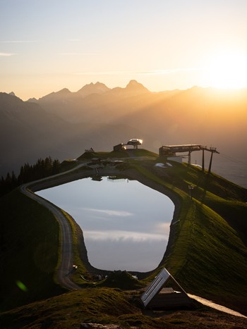 Speicherteich mit Bergstation bei Sonnenaufgang, Leogang