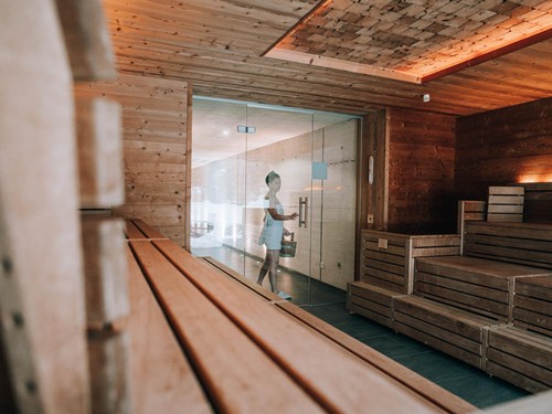 Person mit Holzeimer betritt die Sauna, Puradies Leogang