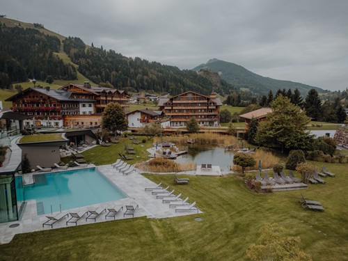 Gesamtansicht mit Infinity Pool und Naturbadeteich unter bewölktem Himmel, Naturresort Puradies, Leogang, Salzburger Land Infinity Pool und Naturbadeteich, Gesamtansicht, Puradies Leogang