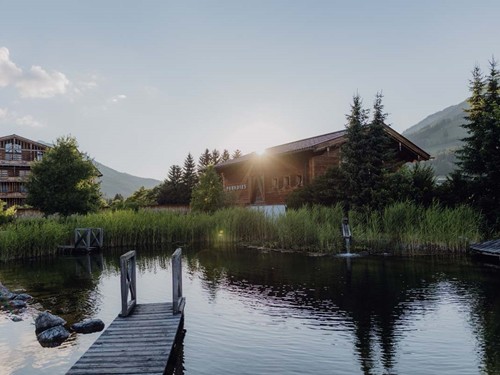 Naturbadeteich mit Traumquartier und Saunahaus im warmen Abendlicht – Naturresort Puradies, Leogang, Salzburger Land Naturbadeteich mit Traumquartier und Saunahaus, Puradies Leogang