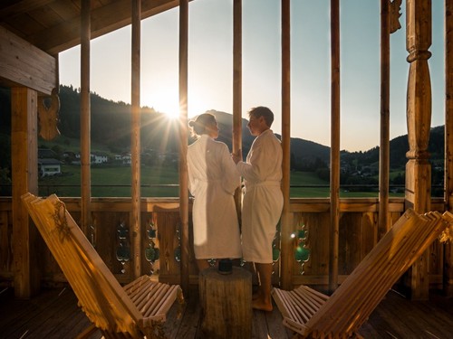 Personen im Bademantel auf Zimmerbalkon bei Sonnenuntergang, Puradies Leogang