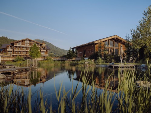 Naturbadeteich mit Traumquartier und Saunahaus im Hintergrund – Naturresort Puradies, Leogang, Salzburger Land Naturbadeteich mit Traumquartier und Saunahaus, Naturresort Puradies in Leogang