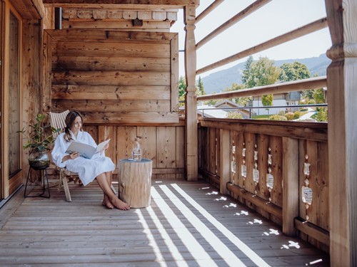 Person im Bademantel beim Lesen auf dem Balkon – Naturresort Puradies, Leogang, Salzburger Land Person im Bademantel beim Lesen auf dem Balkon, Puradies Leogang