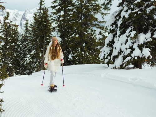 Person mit Schneeschuhen auf präparierter Loipe im Winterwald – Naturresort Puradies, Leogang, Salzburger Land Person mit Schneeschuhen im Winterwald, Naturresort Puradies