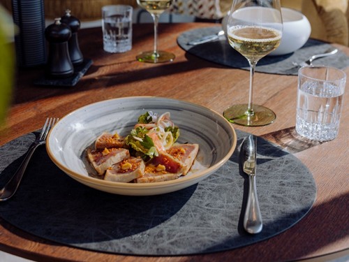 Gedeckter Tisch mit angerichtetem Gericht und Weißwein im Naturresort Puradies, Leogang, Salzburger Land Angerichtetes Gericht mit Weißwein am gedeckten Tisch, Puradies Leogang