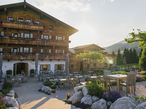 Hotel Puradies with Wooden Balconies, Flower Boxes and Sun Terrace Against a Mountain Backdrop in Summer – Naturresort Puradies, Leogang, Salzburger Land Hotel Puradies with wooden façade, flower balconies and sun terrace in summer, mountains in the background, Naturresort Puradies in Leogang